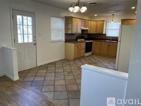 A kitchen with wooden cabinets and a tiled floor.