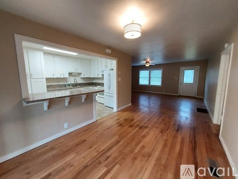 A kitchen with wooden floors and white cabinets is available.