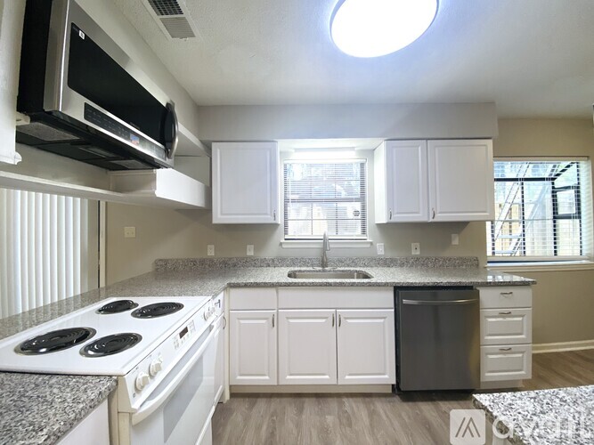 A kitchen with white cabinets and a granite countertop.