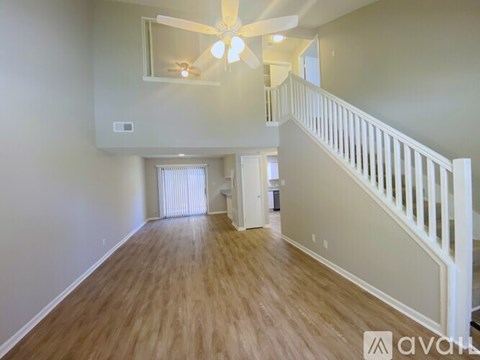 A spacious room with a wooden floor and a staircase leading to the upper level.