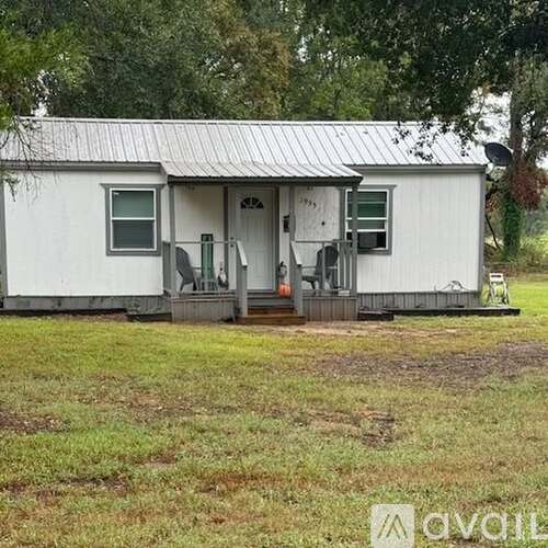 A white house with a metal roof and a porch.