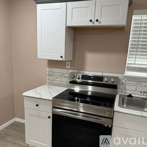A kitchen with a stove top oven and white cabinets.