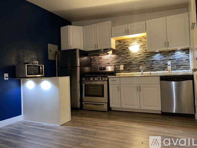 A kitchen with dark blue walls and white cabinets.