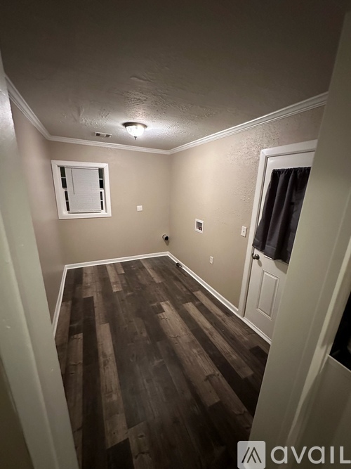 A room with wooden flooring and a window with closed curtains.