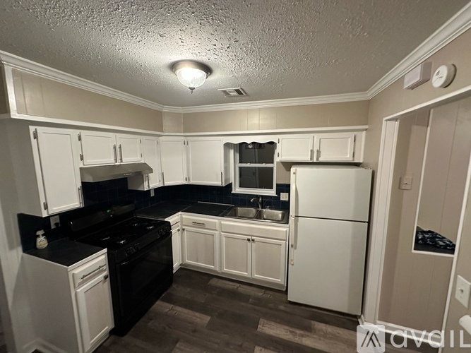 A kitchen with white cabinets and black appliances.
