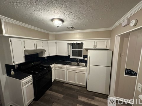 A kitchen with white cabinets and black appliances.