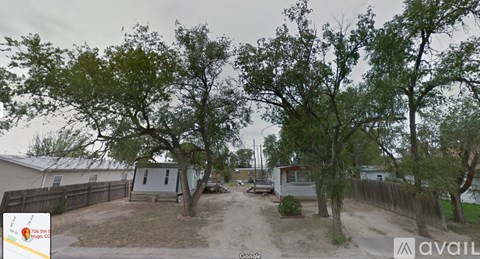 A street view of a residential area with houses and trees.