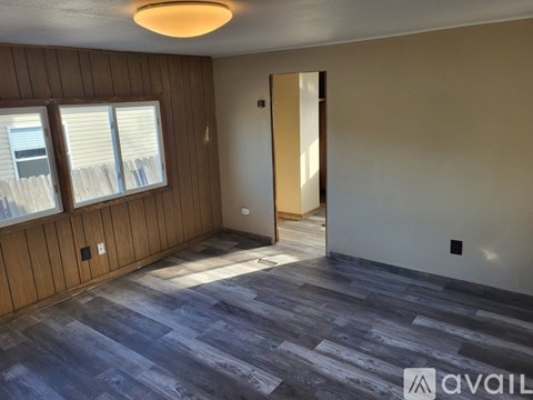 A room with wooden paneling and a large window with blinds.