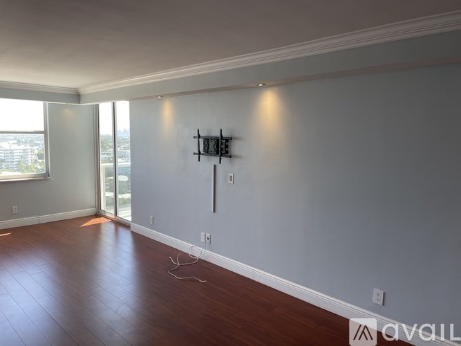 A room with a wooden floor and a wall-mounted TV.