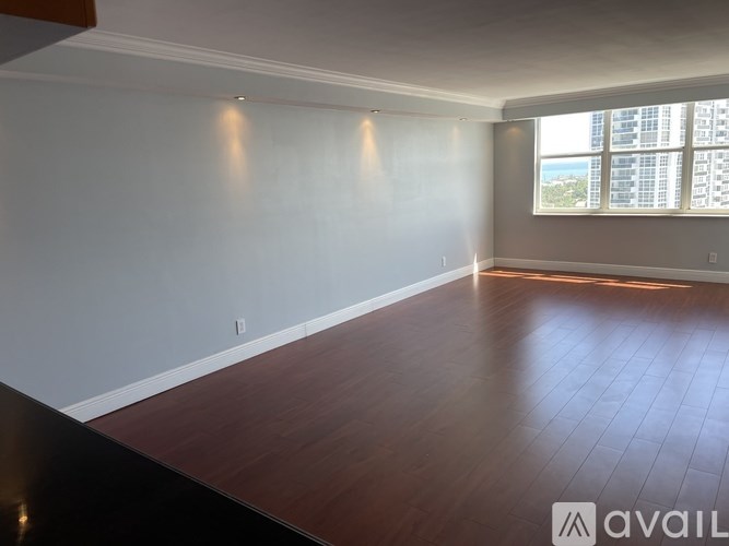 A room with wooden flooring and a window overlooking a cityscape.