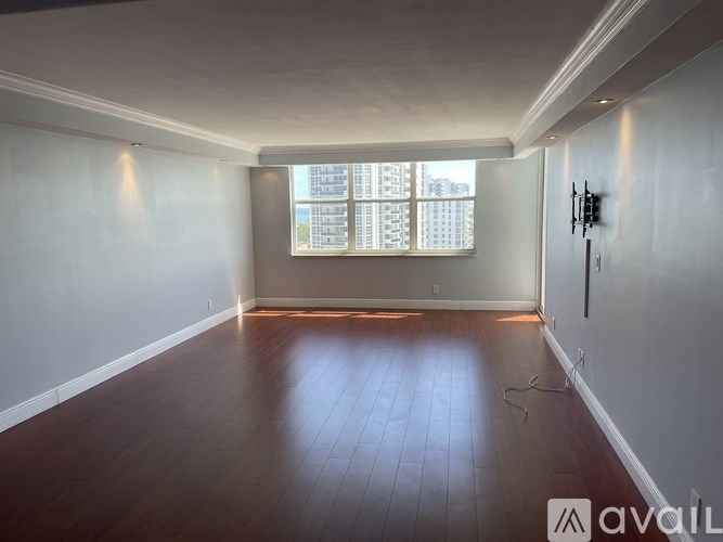 A room with wooden floors and a window letting in sunlight.