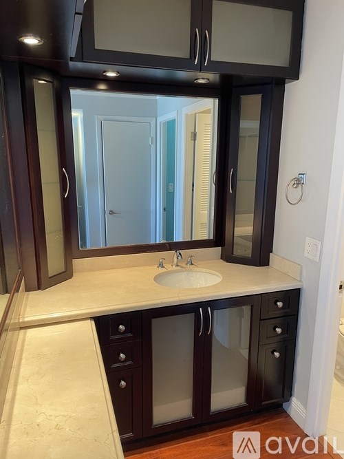 A bathroom with a sink, mirror, and cabinets.