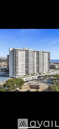 A tall white building with a parking lot in front of it.