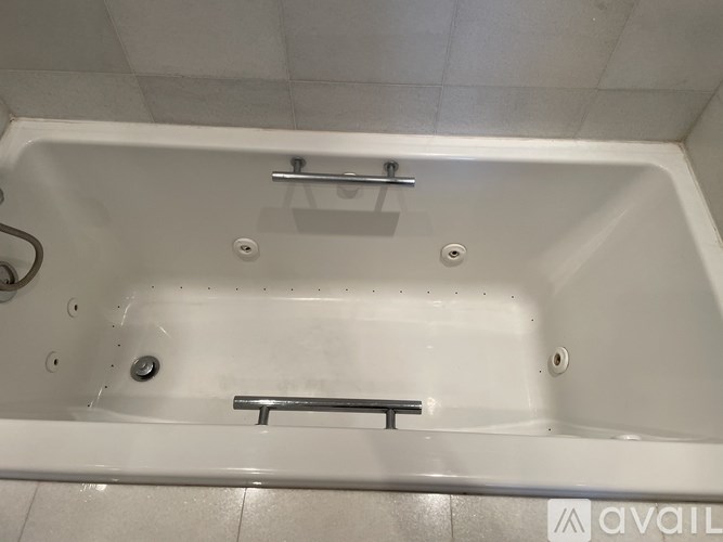 A white bathtub with a silver faucet and a silver grab bar.