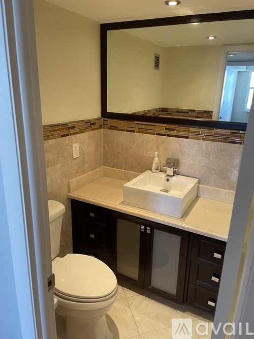 A bathroom with a toilet, sink, and mirror.