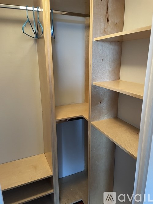A wooden closet with a hanger and a shelf.