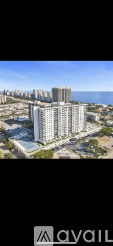 A tall building with a flat roof is surrounded by other buildings.
