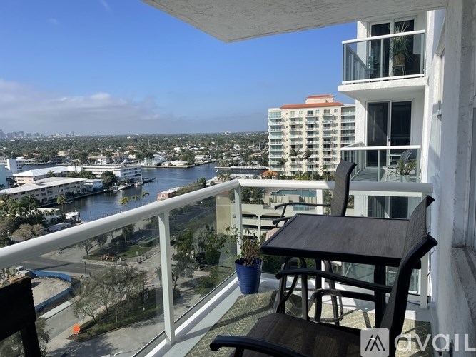 A balcony with a table and chairs overlooking a cityscape.
