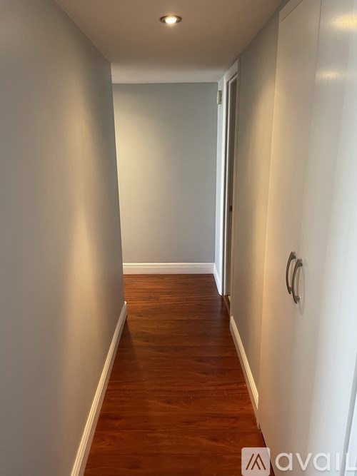 A long hallway with wood floors and white walls.