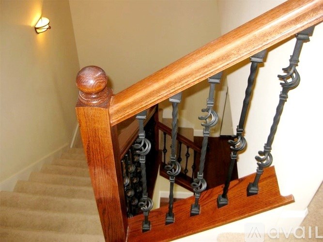 A staircase with a wooden handrail and black balusters.