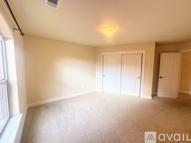 A room with a carpeted floor, two doors, and a window.