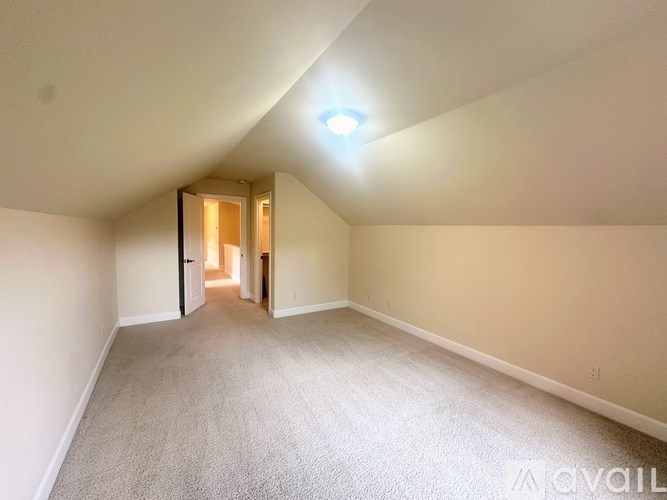 A carpeted room with a light on the ceiling and a doorway leading to another room.