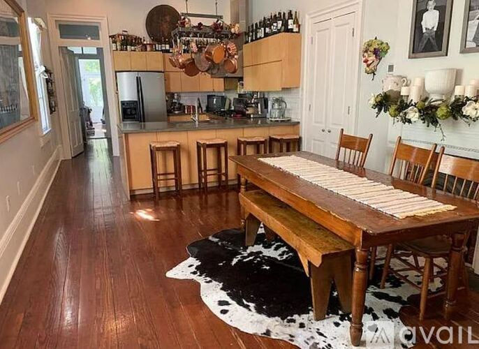 A kitchen with a wooden table and chairs and a cowhide rug on the floor.