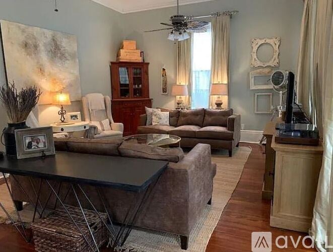 A living room with a brown couch, a black coffee table, and a ceiling fan.
