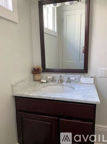 A bathroom vanity with a marble countertop and a large mirror above it.