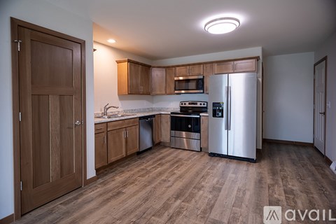 A kitchen with wooden cabinets and a stainless steel refrigerator.