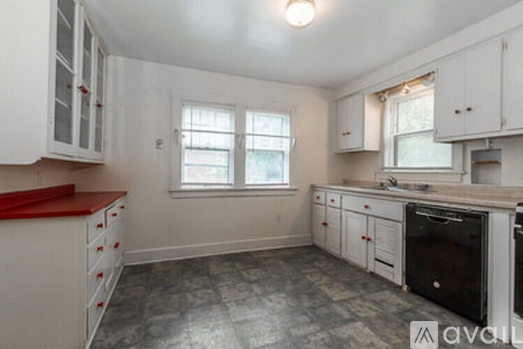 A kitchen with white cabinets and a red countertop.