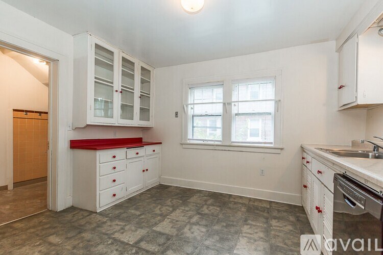 A kitchen with white cabinets and a red countertop.