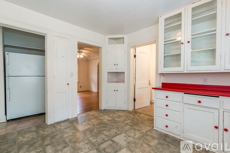 A kitchen with white cabinets and a red counter.