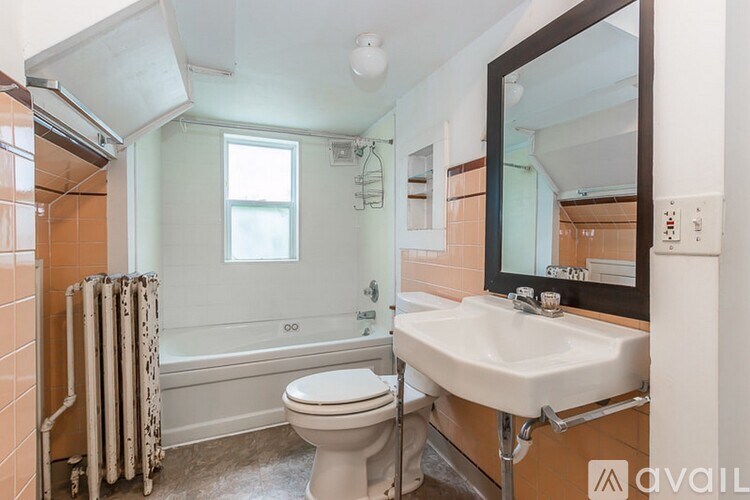 A bathroom with a toilet, sink, and a window.