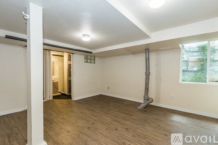 A room with wooden flooring and a window on the right side.