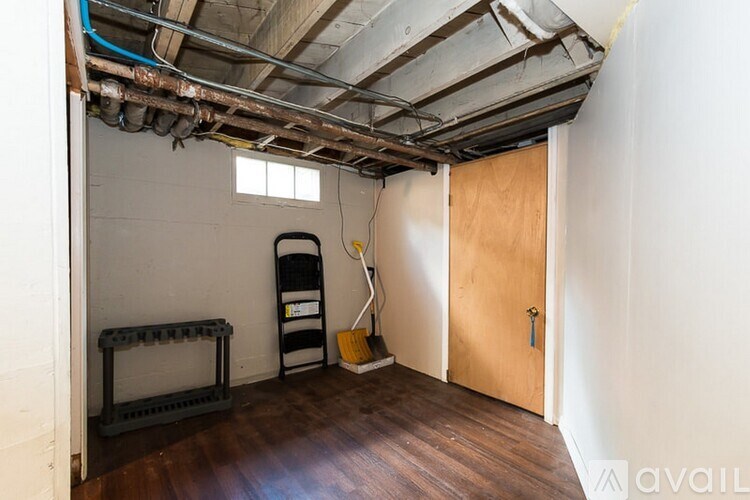 A room with a wooden floor and a door, a window, and a vacuum cleaner.
