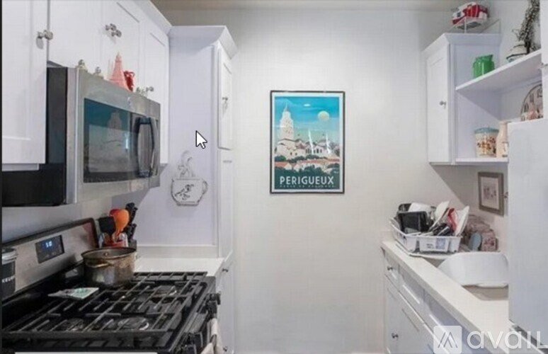 A kitchen with a stove, microwave, and a poster on the wall.