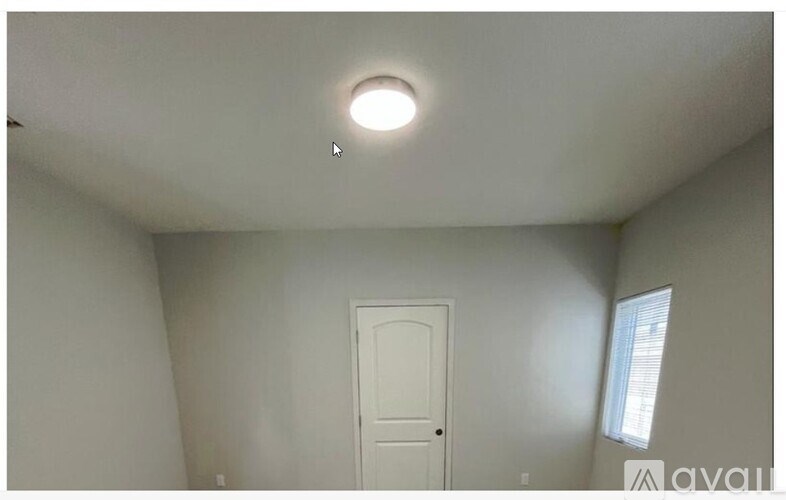 A room with a white door and a window on the right side.