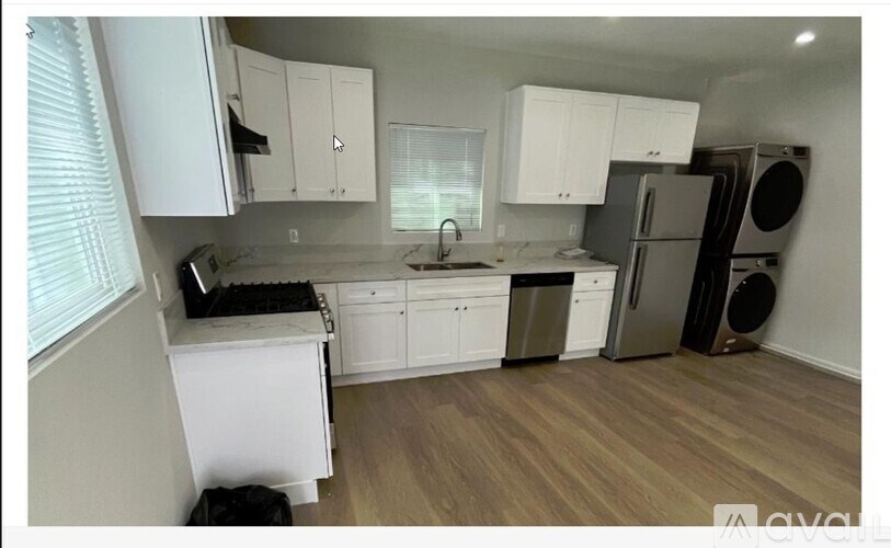 A kitchen with white cabinets and a wooden floor.