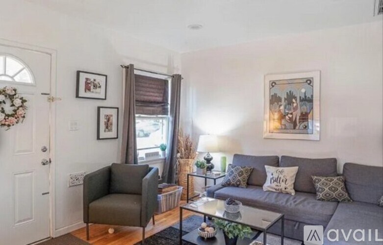 A living room with a grey couch, a grey armchair, and a glass coffee table.