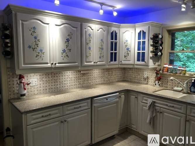 A kitchen with white cabinets and a blue light above.
