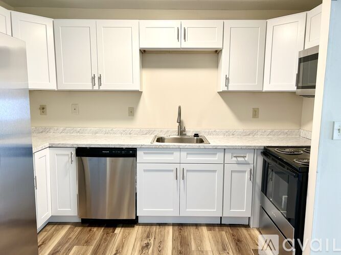 A kitchen with white cabinets and a wooden floor.