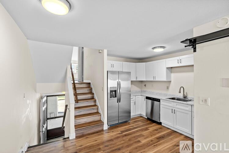 A kitchen with white cabinets and a stainless steel refrigerator.
