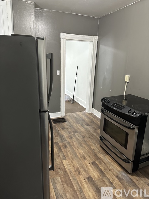 A kitchen with a black fridge, black oven and wooden floor.