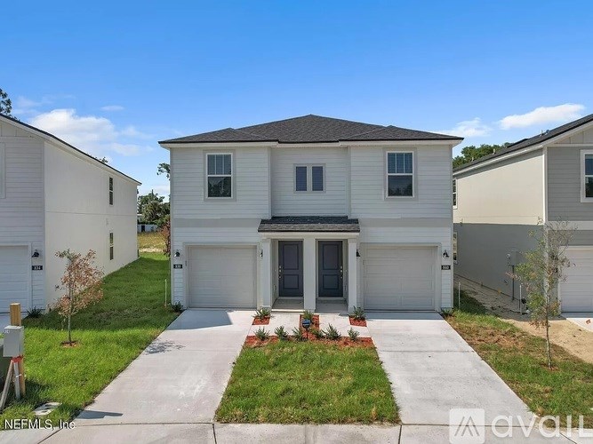A white house with a grey roof is surrounded by other similar houses.