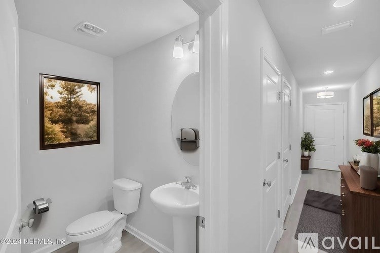 A white bathroom with a toilet, sink, and mirror.