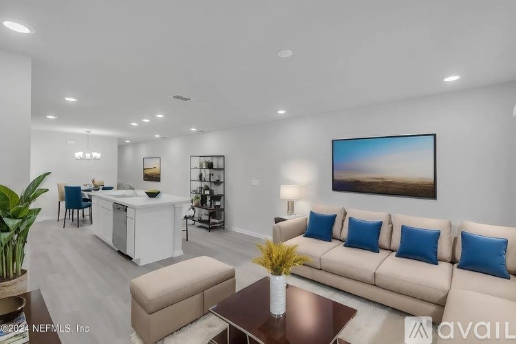 A modern living room with a large couch, a coffee table, and a kitchen area in the background.
