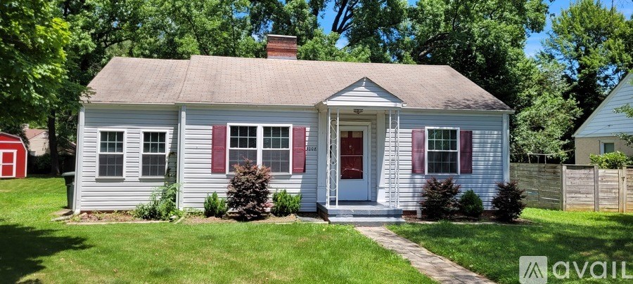 A small house with a red door and red window shutters is for sale.