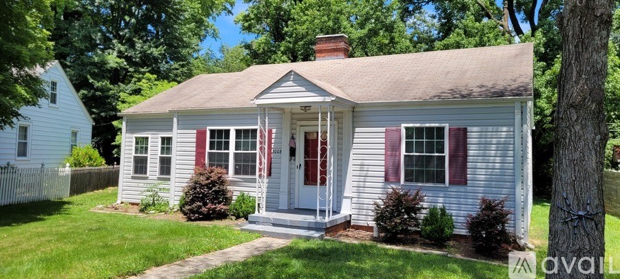 A small house with red shutters and a white door is for sale.