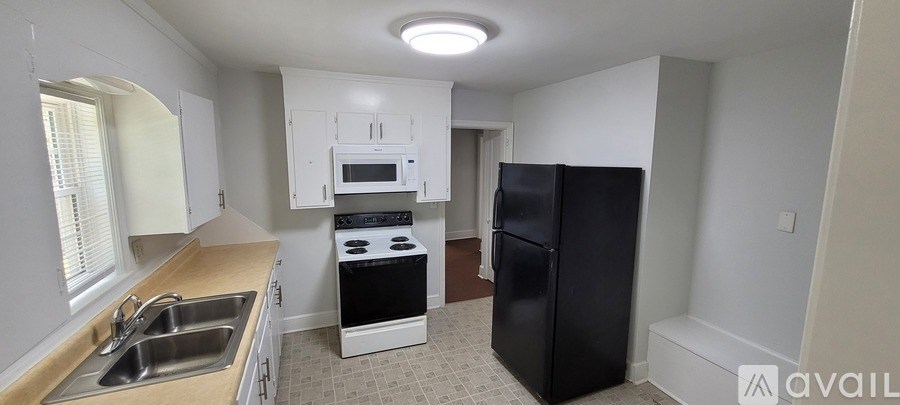 A kitchen with black appliances and white cabinets.